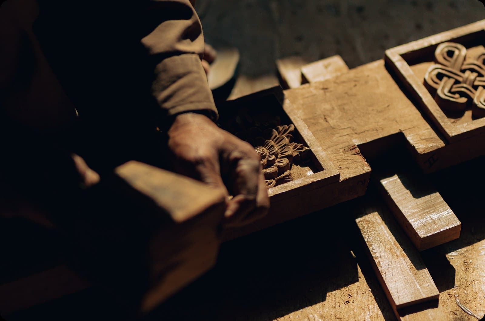 Hands assembling intricately carved wooden panels