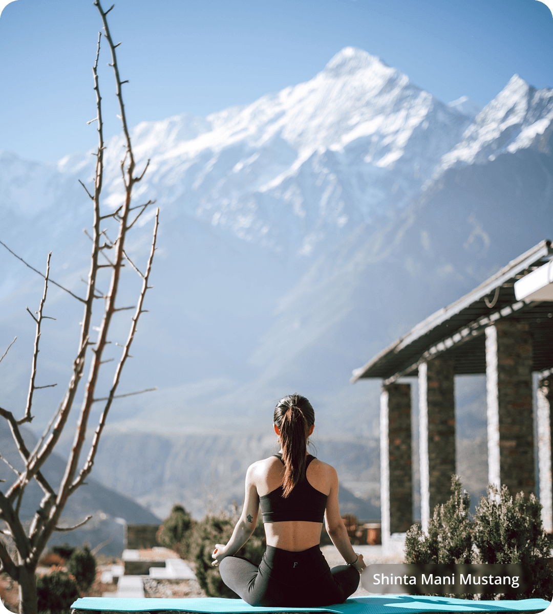 Guest meditating outdoors with snow-capped Himalayan peaks beyond
