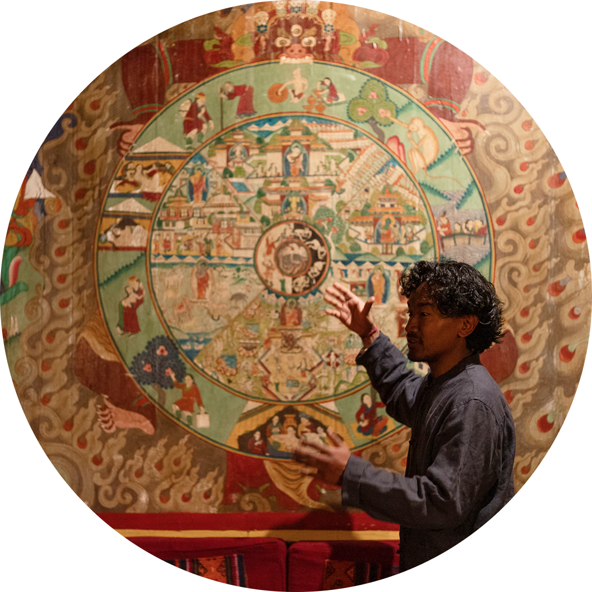 Host gesturing toward a painted mandala mural