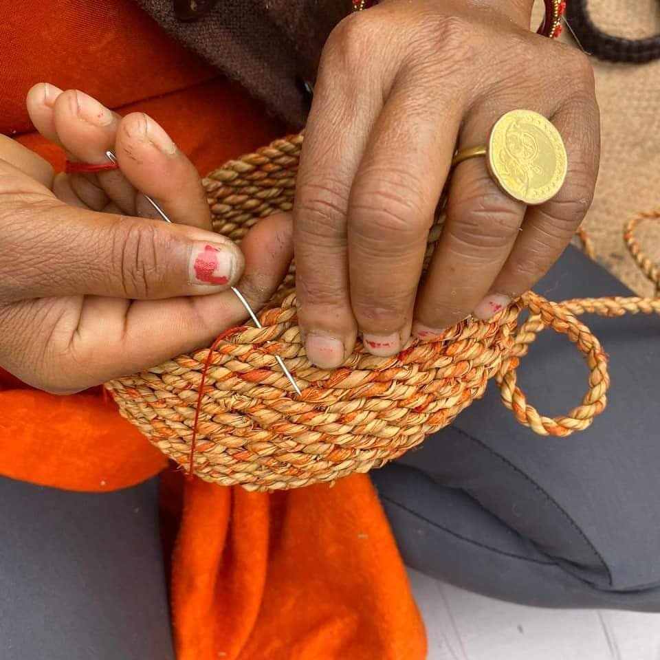 Artisan weaving a coiled basket with needle and thread